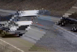 A tractor hauls a fltabed trailer and its load. t(Photo credit: Shutterstock)
