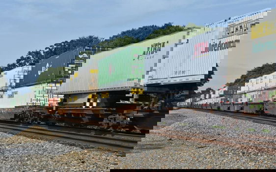 Intermodal railcars, in assorted colors, are stacked on rail cars.