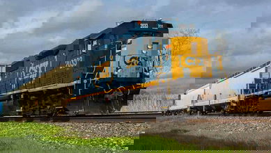 A photograph of a locomotive hauling railcars in a grassy field.