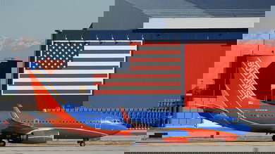 Blue/orange plane beneath a giant American flag.