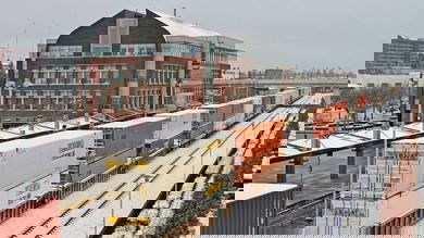 A photograph of a train hauling intermodal containers traveling through a downtown area in wintertime.