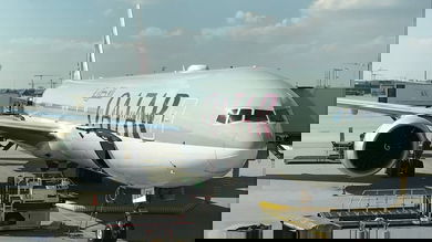 Large, gray Qatar Airways at airport gate.
