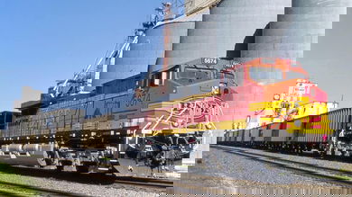A photograph of a train in front of silos.