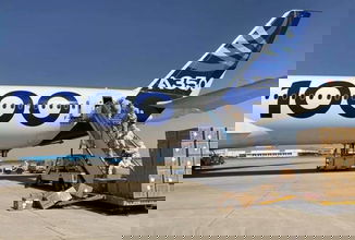 A large white plane gets loaded with boxes of face masks.