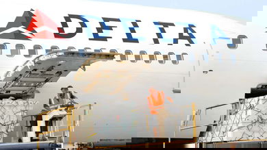 Cargo loaded in side door of white jetliner.