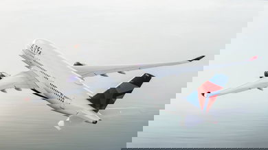 A large white jet flies over the clouds.