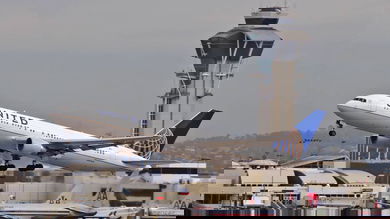 A white United plane takes off with control tower in background.