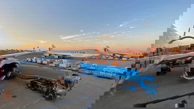 Cargo plane being loaded with beautiful sky in background.at