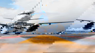 White jet pulled by a tug and aimed right at camera.
