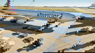 A big silver plane being loaded with cargo.