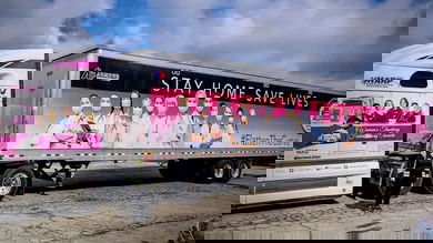 Shelley Uvanile-Hesch standing in front of her tractor-trailer, wrapped with the message "Stay Home. Save Lives"