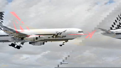 Big white jet with wheels down for landing.