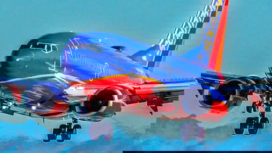 Bright blue and orange Southwest jet comes in for landing wheels down.