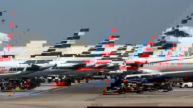 Red, white and blue tails of American Airlines planes at terminal gates.