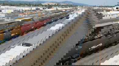 A photograph of a line of boxcars, a line of tank cars and a line of intermodal containers, all parked at a rail yard.