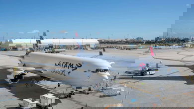 A white jet parked on airport ramp.