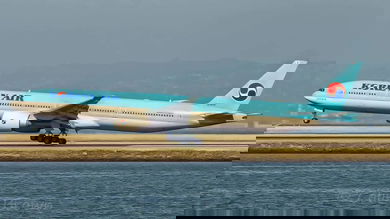 A light blue Korean Air jet lands on runway by water.
