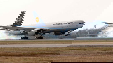 A white Lufthansa plane touches down on runway.