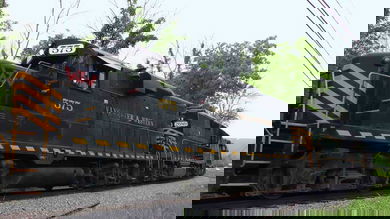 A photograph of a train locomotive. There are trees behind the train.