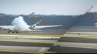 A big white jet heading away lifts nose off runway