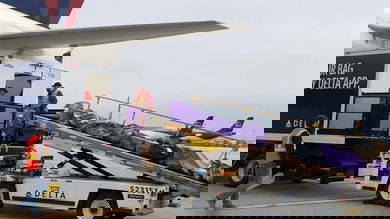 Mail bags being loaded with a conveyor onto a passenger airplane.