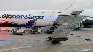 Big white 747 freigher with nose cone up to load cargo.