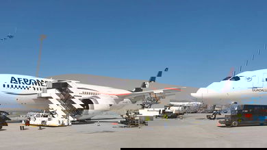 A white passenger jet with stairs leading up to front door.