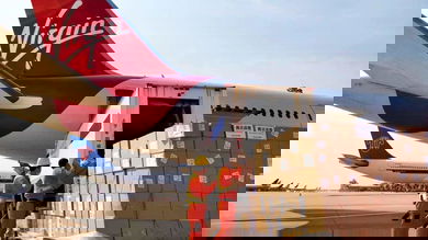 Boxes being loaded in rear door of plane with red tail.