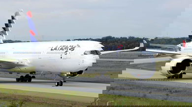 A big white jet with blue tail coming toward camera on taxiway.