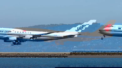 Big white jumbo jet comes in for landing over water at San Francisco Airport