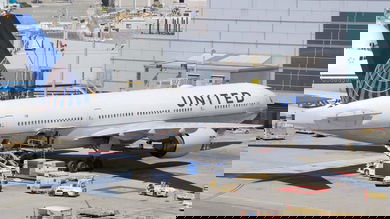 White jet, blue tail, United Airlines at airport gate.