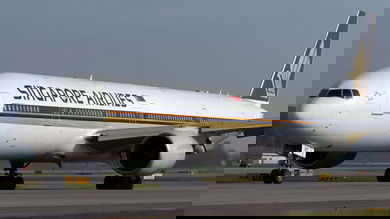A big white Singapore Airlines plane, viewed at 45-degree angle from front as plane sits on ground.