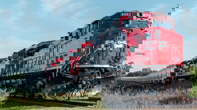 A photograph of a Canadian Pacific train traveling through a grassy field.