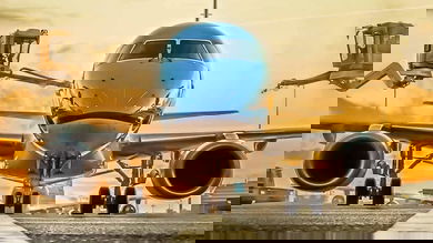 Shiny blue plane coming straight at camera, with morning sun in the background.