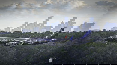A dark blue United Airlines jet comes in for landing, side view right above the tree tops. United posted a $1.6 billion loss Tuesday.