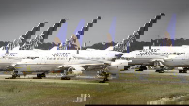 White jets with blue tails from United Airlines lined up on an inactive taxiway at George Bush Intercontinental Airport in Houston. They're in storage.