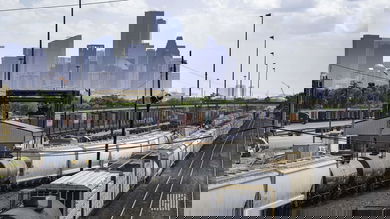A photograph of trains at a rail yard. There are tall city buildings in the background.