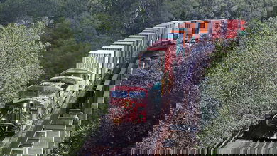 A photograph of a Canadian Pacific train carrying containers. The train is traveling through a forest.