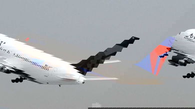 A big white Delta jet with blue tail early in takeoff. Delta wants to take out some seats in planes to make way for cargo.