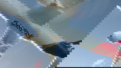 A big Qantas jet takes off in bright skies right over photographer, with logo clearly seen on bottom of fuselage. Qantas' international business is suffering.