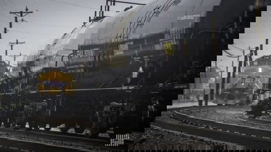 A photograph of a Union Pacific train behind a train of tank cars. They are at a rail yard.