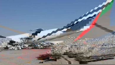 Pallets of humanitarian cargo sit outside next to a big plane waiting to be loaded on a sunny day.