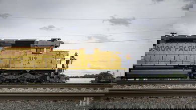 A photographer of a worker standing at the front of a Union Pacific train.