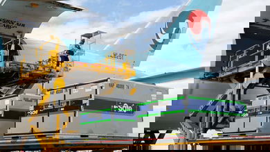Refrigerated containers get lifted onto a light blue cargo plane for Korean Air.