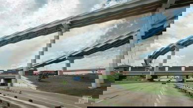 A photograph of a train hauling intermodal containers by a highway overpass.