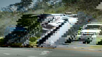 Flipped tractor-trailer on the side of a road.