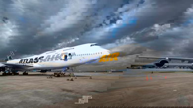 A white Atlas Air jumbo cargo jet on tarmac with dark skies over it.