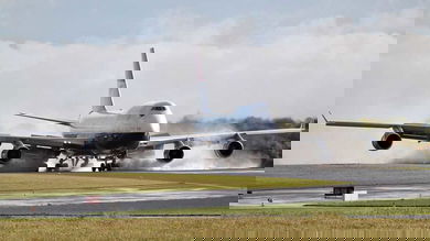 A British Airways 747 touching down on runway with smoke from tires.