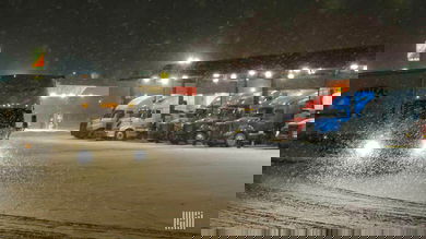 Tractor-trailers at a truck stop on a snowy night.