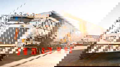 A semi-truck of Watson Transport with a trailer containing a rail car. QSL became full owner of Watson.